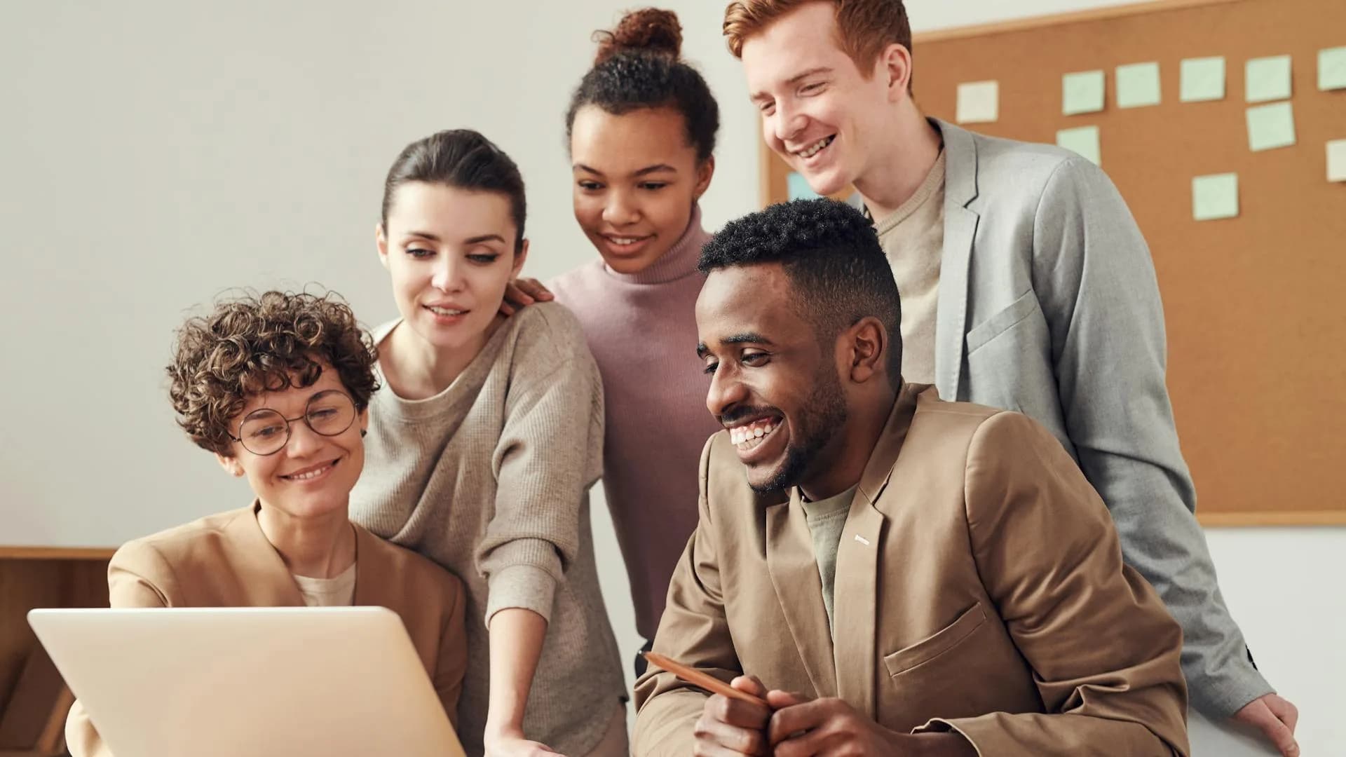 A team gathered around a laptop, smiling together
